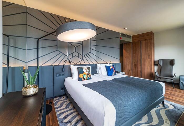 Hotel Clark Budapest: A pet-friendly, gay-friendly hotel room with a bed, pillows, geometric wall design, and modern lighting.