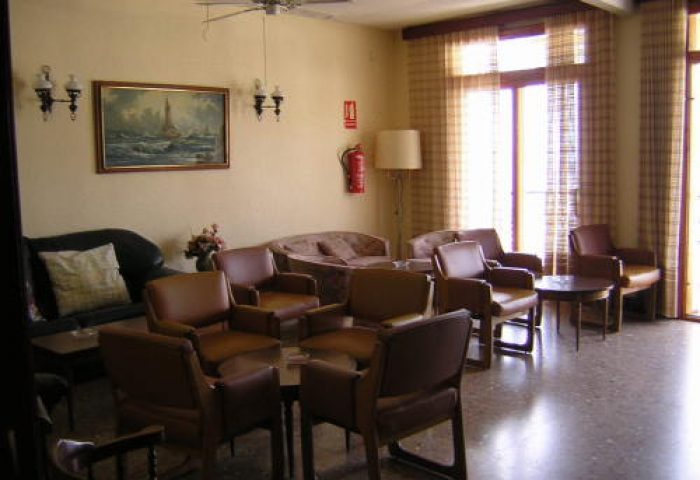 Hotel Condestable's lobby, a gay-friendly hotel. Relaxed seating area with chairs, sofas, and a painting. Welcoming space for gay travelers.