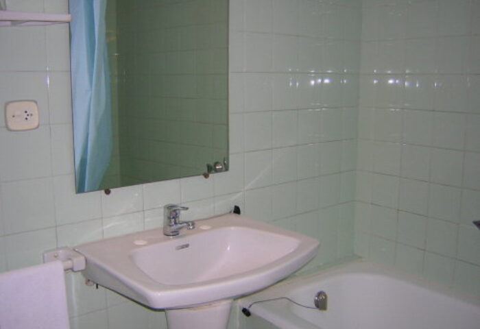 Hotel Condestable bathroom. Sink, mirror, and bathtub with green tile. Gay-friendly hotel option for gay men travelers.