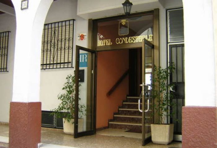 Hotel Condestable entrance. Gay-friendly hotel with glass doors, plants, and stairs. A welcoming stay for gay men travelers.