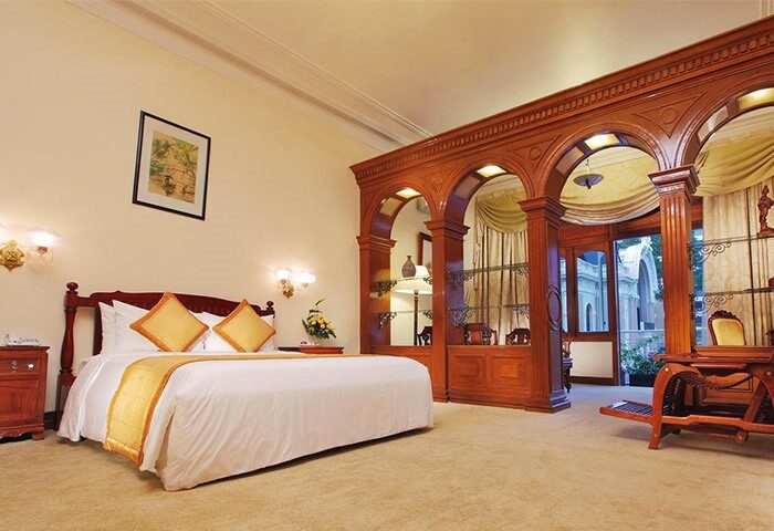 Hotel Continental Saigon gay-friendly hotel room. Luxurious bedroom with wooden archway, desk, and bed. A great choice for gay travelers.