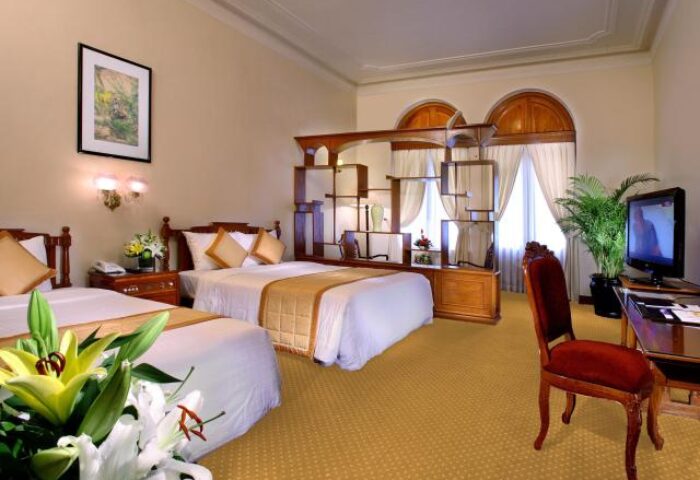 Hotel Continental Saigon gay-friendly hotel room with twin beds, desk, TV, and flowers. A comfortable stay for gay travelers in Saigon.