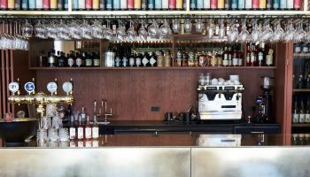 Hotel Danmark by Brøchner Hotels bar. Bottles, glasses, and a beer tap are arranged above the counter. Gay-friendly hotel for gay travelers.