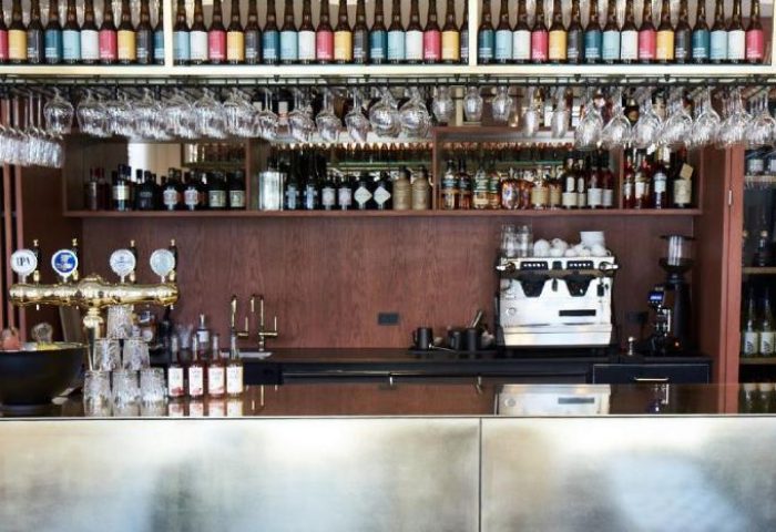 Hotel Danmark by Brøchner Hotels bar. Bottles, glasses, and a beer tap are arranged above the counter. Gay-friendly hotel for gay travelers.