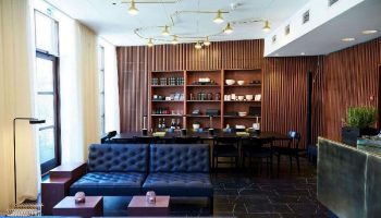 Hotel Danmark by Brøchner Hotels' gay-friendly lounge area. Features stylish seating, wood paneling, and a well-stocked shelf.