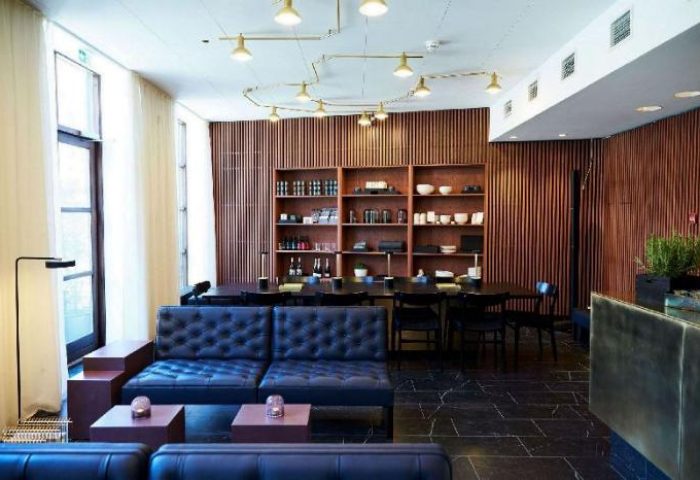 Hotel Danmark by Brøchner Hotels' gay-friendly lounge area. Features stylish seating, wood paneling, and a well-stocked shelf.