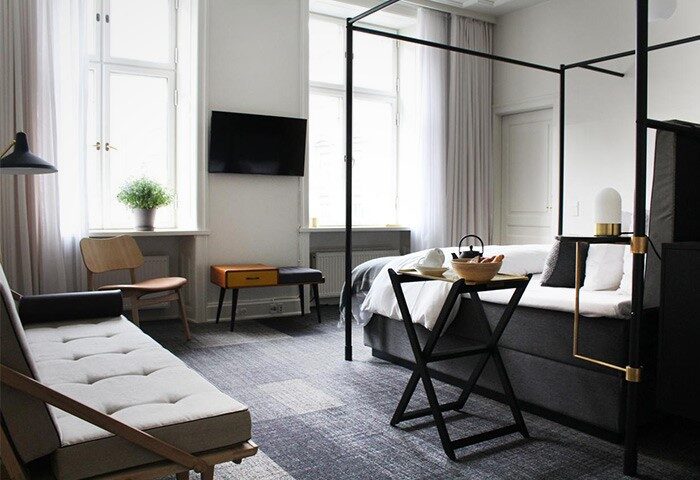 Hotel Danmark by Brøchner Hotels room interior. Gay-friendly hotel with four-poster bed, sofa, and modern design. Travel destination for gay men.