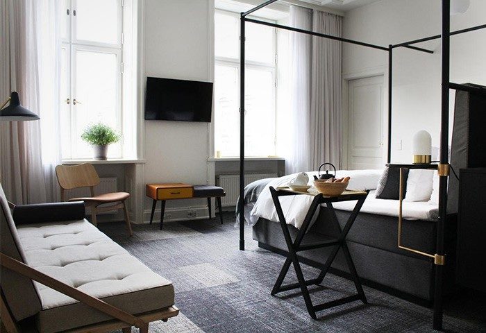 Hotel Danmark by Brøchner Hotels room interior. Gay-friendly hotel with four-poster bed, sofa, and modern design. Travel destination for gay men.
