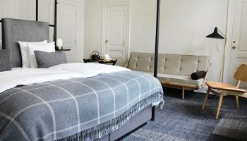 Hotel Danmark by Brøchner Hotels room. Gay-friendly hotel with bed, couch, chair, and minimalist decor. Perfect for gay men travel in Copenhagen.