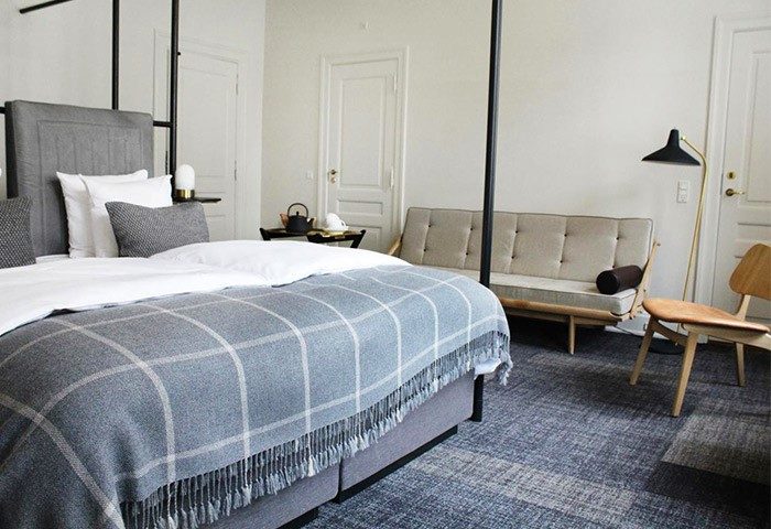 Hotel Danmark by Brøchner Hotels room. Gay-friendly hotel with bed, couch, chair, and minimalist decor. Perfect for gay men travel in Copenhagen.