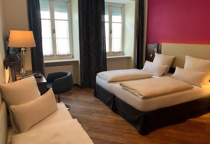 Hotel Deutsche Eiche gay-friendly room. Twin beds, desk, chair, and daybed in a cozy, modern space. Ideal for gay travelers.