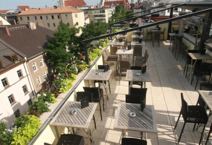 Hotel Deutsche Eiche's rooftop terrace. Gay-friendly hotel in Munich, Germany. Tables, chairs, and city views. Gay travel advice.