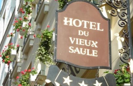 Hotel Du Vieux Saule, a gay-friendly, pet-friendly hotel. Facade with flower boxes and a sign with the hotel's name and star rating.