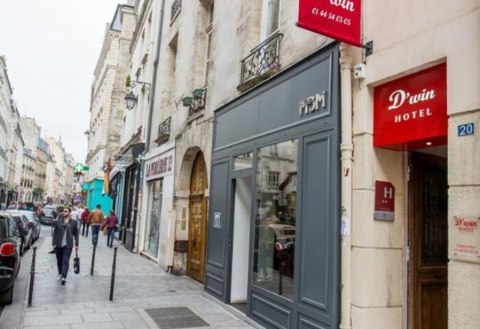 Hotel Dwin, a gay-friendly, pet-friendly hotel in Paris. The hotel's entrance is visible on a Parisian street with its red sign. A top choice for gay travel.