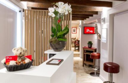 Hotel Dwin's lobby. Gay-friendly, pet-friendly hotel. White reception desk, orchids, teddy bear, and view to the restaurant. Beams on the ceiling.