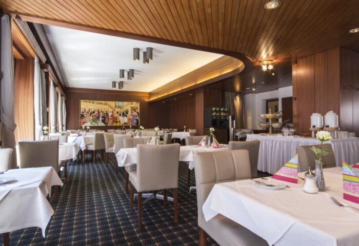 Hotel Europäischer Hof's restaurant. Gay-friendly hotel with tables set for dining. Wood-paneled walls, carpeted floor, and buffet.