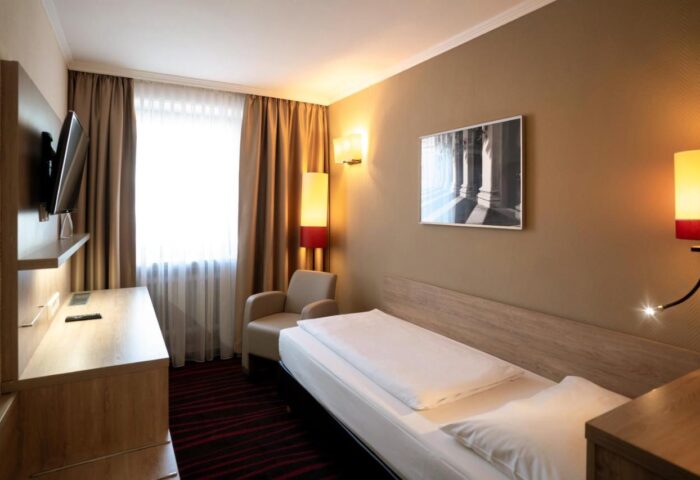 Hotel Europäischer Hof gay-friendly room. Single bed, armchair, TV, and desk in a cozy, well-lit space. Ideal for gay travelers.