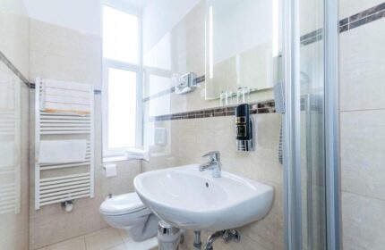 Bathroom at Gay-Friendly Hotel Expo Frankfurt City Centre. Sink, shower, and towel rack. Modern design, clean, comfortable. Perfect for gay travelers.