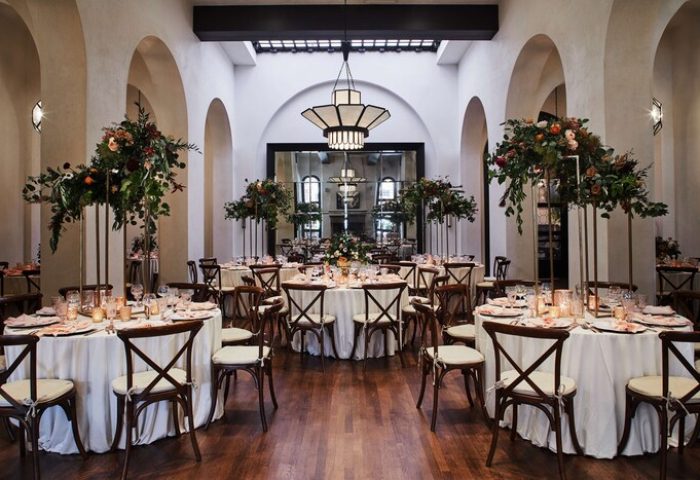Hotel Figueroa, In The Unbound Collection By Hyatt ballroom. Round tables with floral centerpieces, set for a gay-friendly event. Arched architecture.