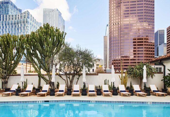 Hotel Figueroa's pool, a gay-friendly Unbound Collection by Hyatt. Lounge chairs line the pool with city views. #gaytravel