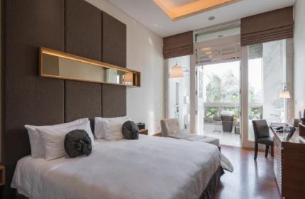 Hotel Fort Canning gay-friendly hotel room. King bed with white linens, brown headboard, and balcony. Upscale gay travel lodging.
