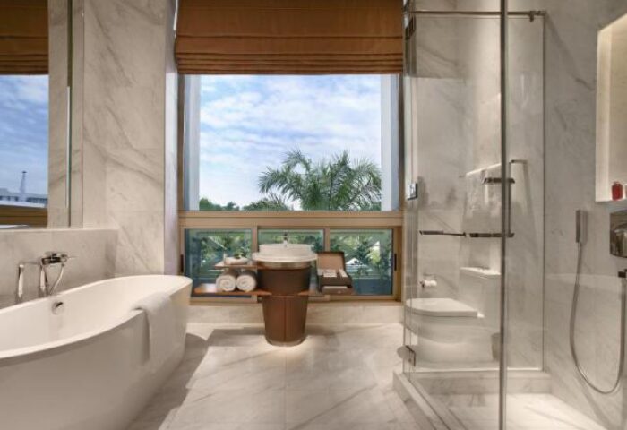 Hotel Fort Canning gay-friendly hotel bathroom. Bathtub, shower, and sink with a view of the outside. Marble tile and modern fixtures.