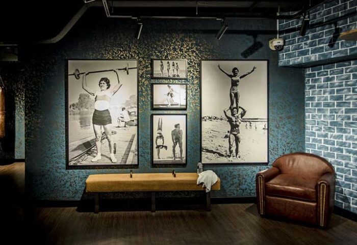 Hotel G Singapore gay-friendly gym with vintage photos of athletes. Leather chair, punching bag, & workout bench. Gym decor.