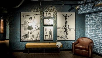Hotel G Singapore gay-friendly gym with vintage photos of athletes. Leather chair, punching bag, & workout bench. Gym decor.