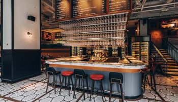 Hotel G Singapore's gay-friendly bar. Stylish interior with bar stools, wine glasses hanging above, and a menu board. A great spot for drinks.