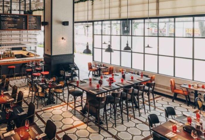 Hotel G Singapore's gay-friendly restaurant with stylish decor. Tables are set for dining, with a bar and large windows.