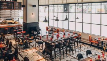 Hotel G Singapore's gay-friendly restaurant with stylish decor. Tables are set for dining, with a bar and large windows.