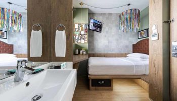 Hotel G Singapore gay-friendly hotel room. Modern design with bed, TV, sink, colorful lamp. Gay travel lodging option.