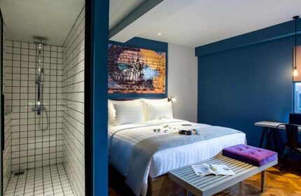 Hotel G Yangon gay-friendly hotel room. Features a shower, bed with art above, and bench. Modern design for gay travelers in Yangon.