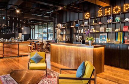 Hotel G Yangon lobby area. Gay-friendly hotel interior with wooden floors, stylish furniture, bar, and shelves with decorative items.