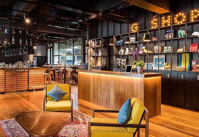Hotel G Yangon lobby area. Gay-friendly hotel interior with wooden floors, stylish furniture, bar, and shelves with decorative items.