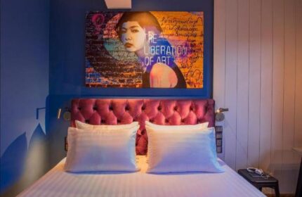 Hotel G Yangon gay-friendly hotel room. Bed with white linens, magenta headboard, and artwork. Modern design for LGBT travelers.
