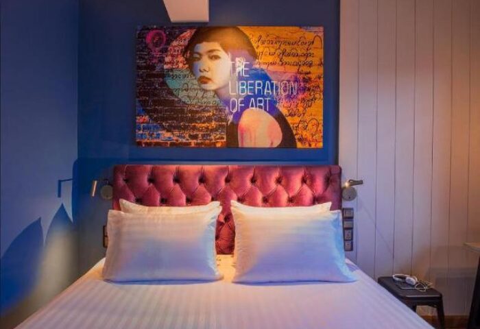 Hotel G Yangon gay-friendly hotel room. Bed with white linens, magenta headboard, and artwork. Modern design for LGBT travelers.