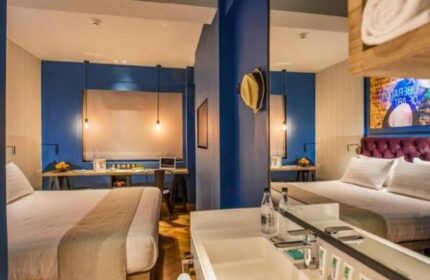 Hotel G Yangon gay-friendly hotel room. Modern design with blue walls, beds, desk, and bathroom. Ideal for gay travel in Yangon, Myanmar.