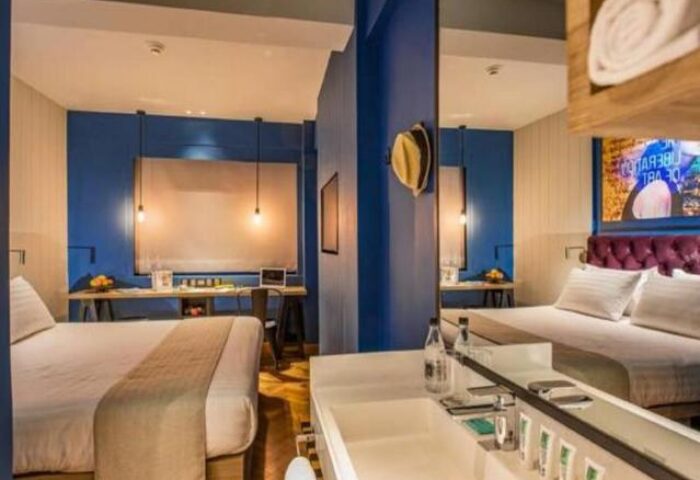 Hotel G Yangon gay-friendly hotel room. Modern design with blue walls, beds, desk, and bathroom. Ideal for gay travel in Yangon, Myanmar.