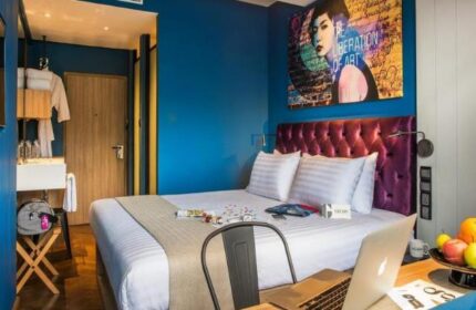 Hotel G Yangon gay-friendly hotel room. Modern design, blue walls, tufted headboard, and workspace. Ideal for gay travel in Yangon, Myanmar.