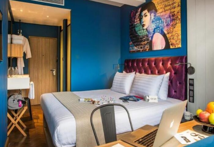 Hotel G Yangon gay-friendly hotel room. Modern design, blue walls, tufted headboard, and workspace. Ideal for gay travel in Yangon, Myanmar.