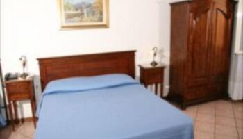 Hotel Giubileo gay-friendly room. Double bed with blue cover, wooden wardrobe and bedside tables. Gay travel advice.