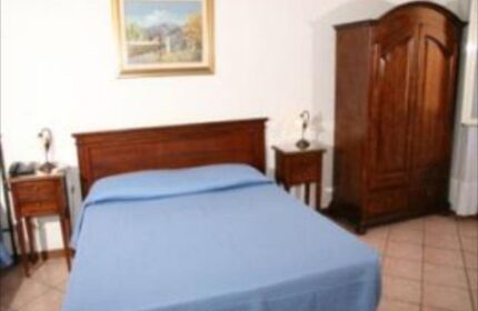 Hotel Giubileo gay-friendly room. Double bed with blue cover, wooden wardrobe and bedside tables. Gay travel advice.