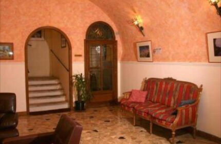 Hotel Giubileo's gay-friendly interior: Seating area with a striped couch, arched doorway to stairs, and warm lighting. A welcoming space.