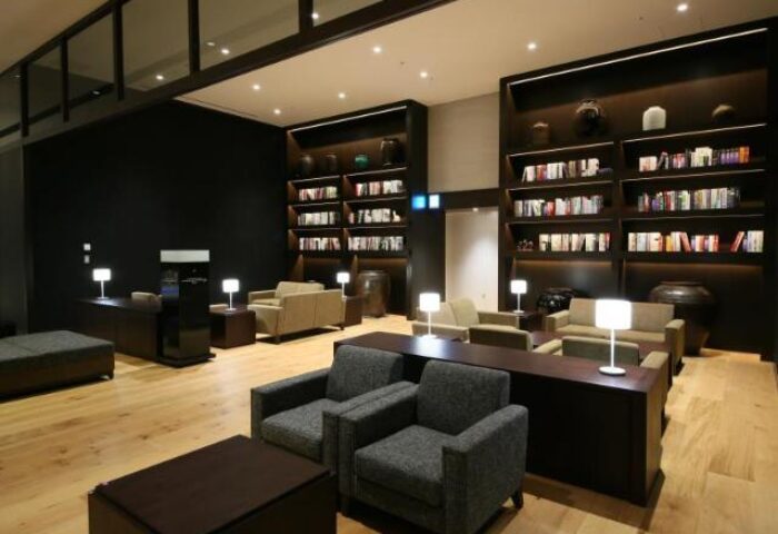 Hotel Gracery Shinjuku's stylish lounge. Bookshelves line the walls, with seating areas for relaxation. A gay-friendly hotel in Tokyo, Japan.