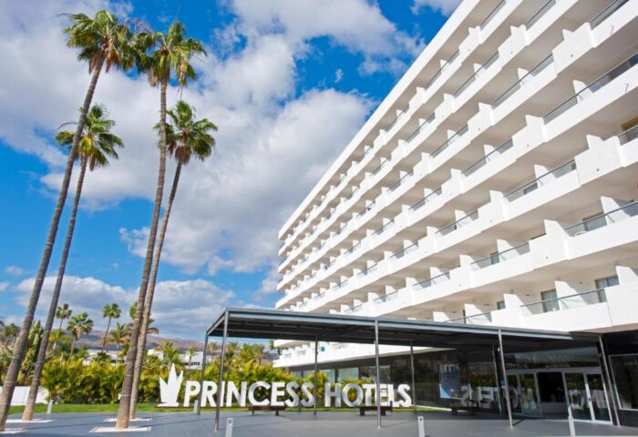 Hotel Gran Canaria Princess Adults Only entrance. Gay-friendly hotel with palm trees, white building, and blue sky. Perfect for gay men's travel.