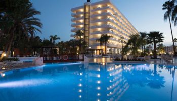 Hotel Gran Canaria Princess Adults Only: Gay-friendly hotel exterior view at dusk. Pool reflects the building's lights. Palm trees surround.