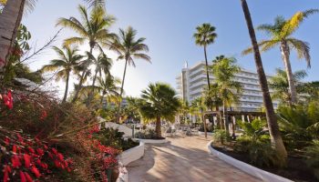 Hotel Gran Canaria Princess Adults Only. Gay-friendly hotel exterior with palm trees, tropical plants, and pathway to the resort.