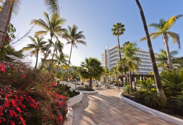 Hotel Gran Canaria Princess Adults Only. Gay-friendly hotel exterior with palm trees, tropical plants, and pathway to the resort.
