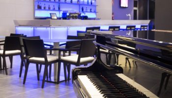 Hotel Gran Canaria Princess Adults Only piano bar. Gay-friendly hotel with elegant bar, tables, and piano. Modern design with blue lighting.